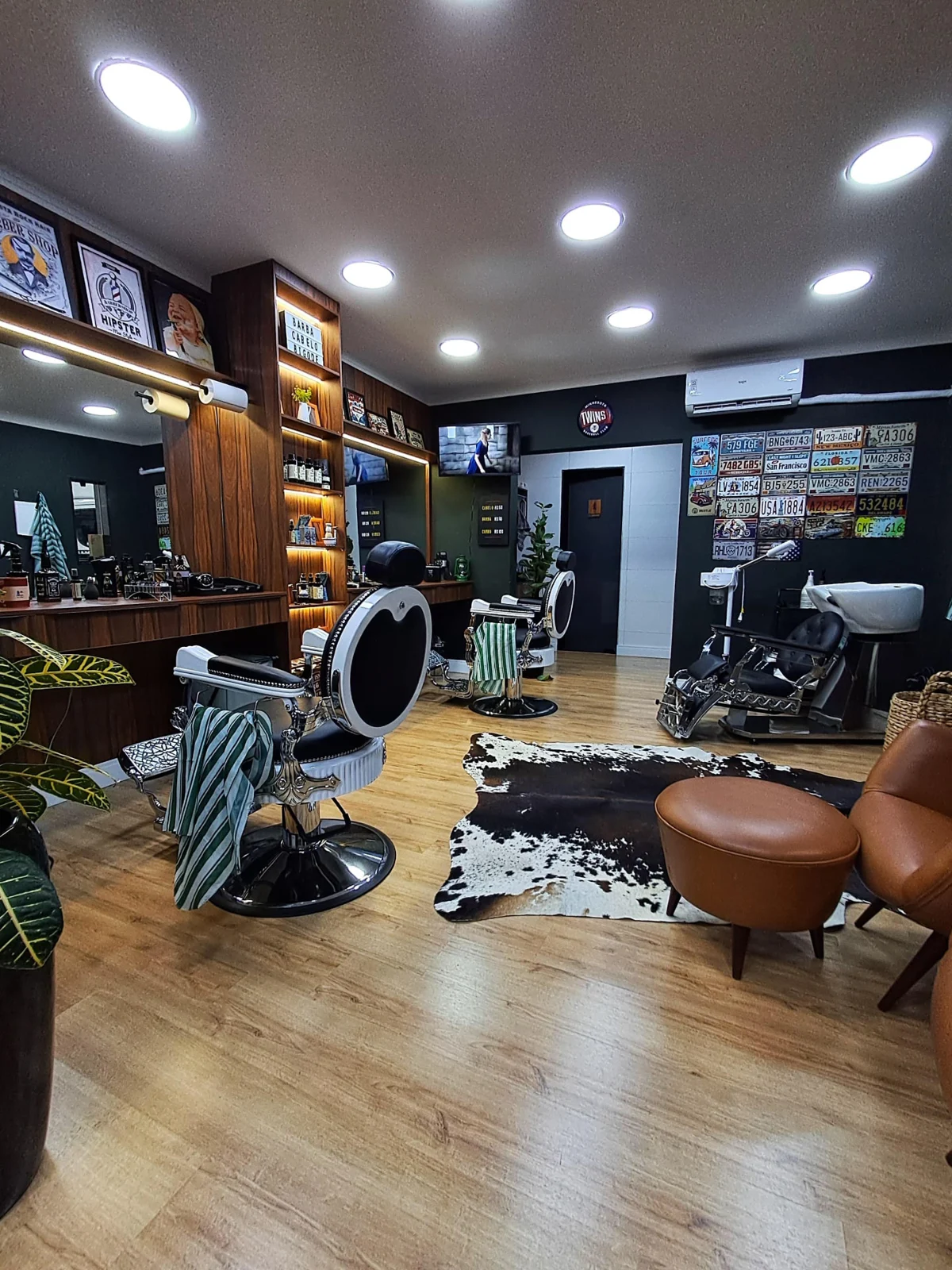 Salão da barbearia com duas cadeiras, bancada de madeira e lavatório